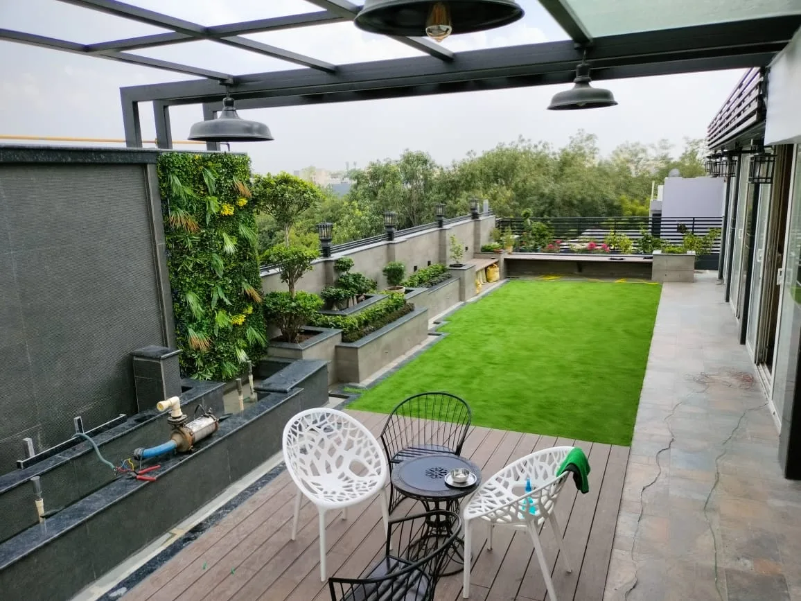 Rooftop lawn and seating beneath a pergola frame